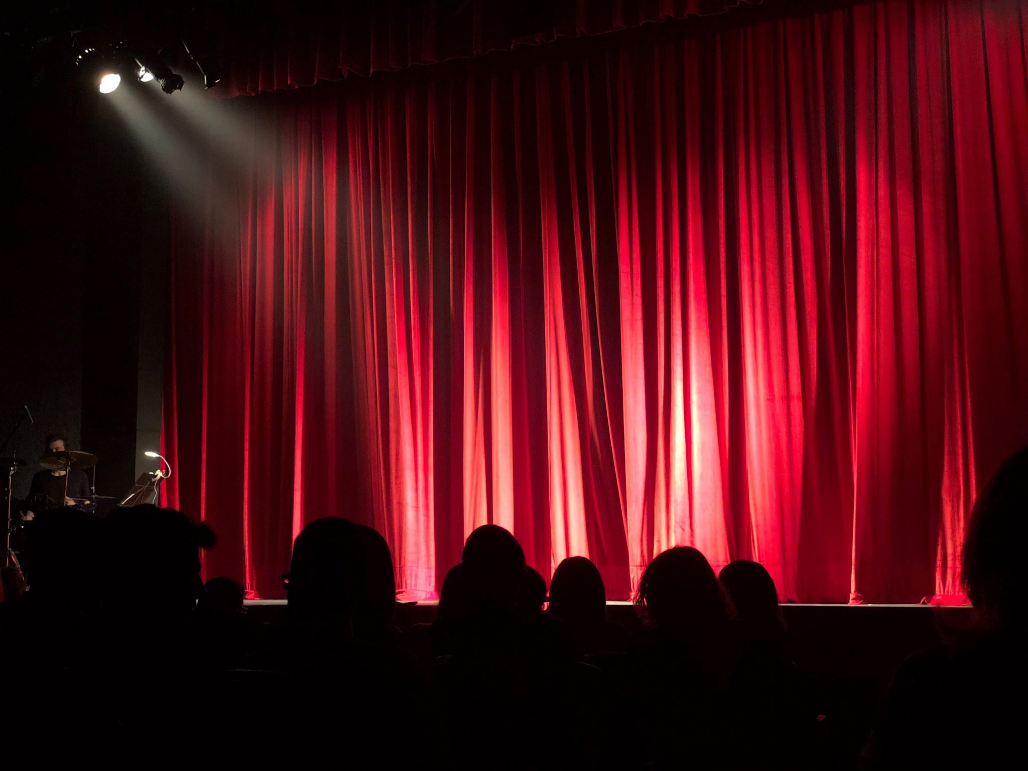 Stage with red curtains and audience watching.